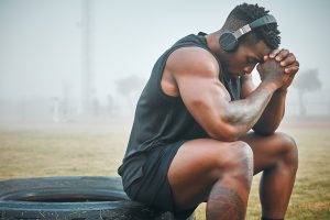 Shot of a muscular young man wearing headphones while exercising outdoors anxiety in athletes