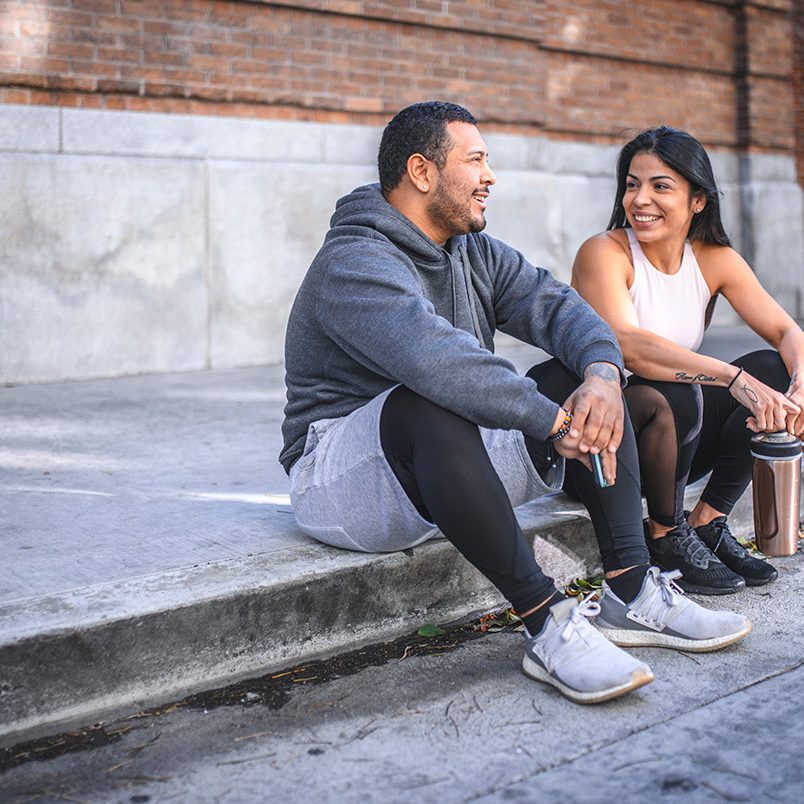 Happy Athletes talking while sitting on sidewalk